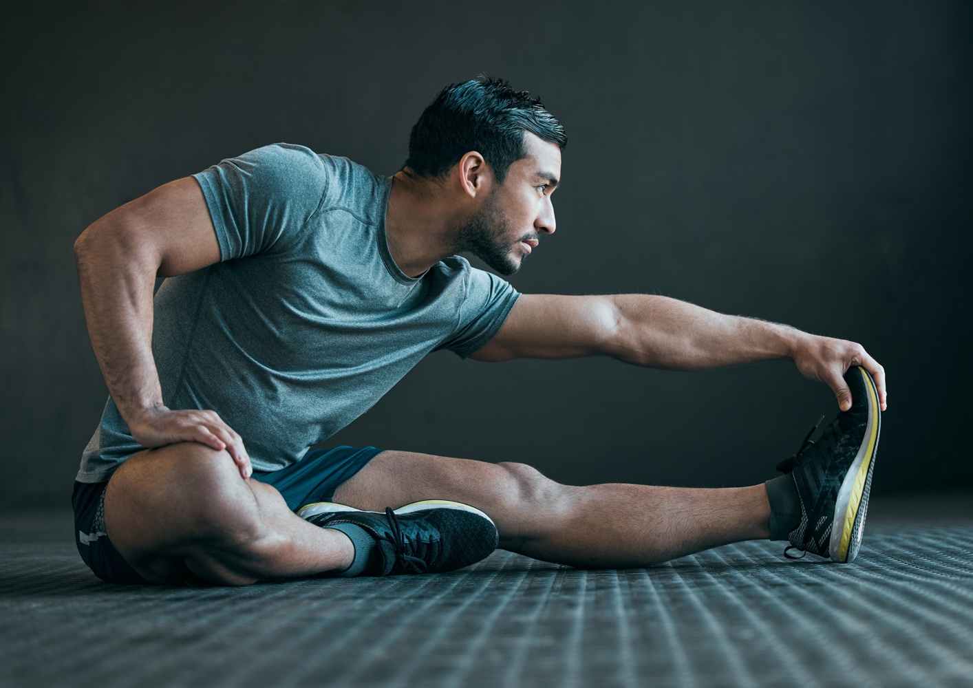 stretching-legs-fitness-man-floor-exercise-training-warm-up-athlete-workout-health-sports-person-with-muscles-wellness-performance-flexibility-gray-background